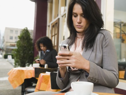 Businesswoman text messaging at outdoor cafe.