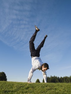Businessman doing handstand outdoors.