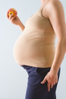 Pregnant woman eating apple. Photographe : Jennifer L. Boggs