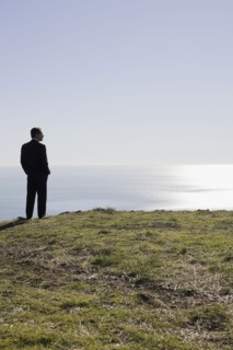 Businessman looking toward ocean. Photographe : PT Images