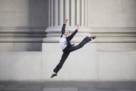 Businesswoman dancing in urban setting. Photographe : PT Images