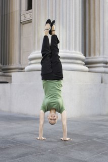 Businesswoman doing handstand on urban sidewalk. Photographe : PT Images