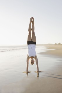 Woman doing yoga on beach. Photographe : PT Images