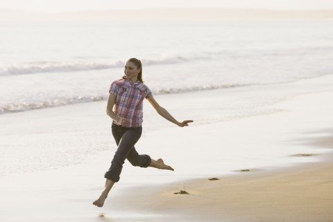 Woman running on beach. Photographe : PT Images
