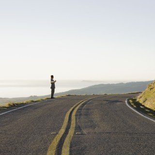 Businessman standing on remote road. Photographe : PT Images