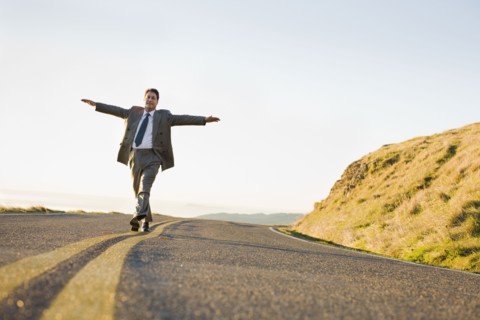 Businessman running on remote road. Photographe : PT Images