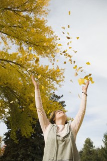 Woman throwing autumn leaves in air.