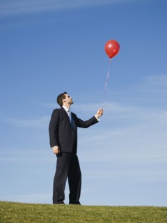 Businessman holding red balloon.