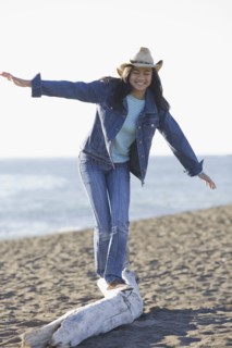 Teenage girl balancing on driftwood. Photographe : PT Images