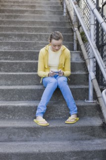 Girl text messaging on steps. Photographe : PT Images