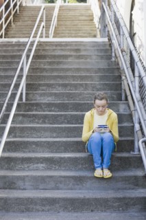 Girl text messaging on steps. Photographe : PT Images