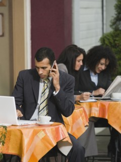 Businessman looking at laptop at outdoor cafe.