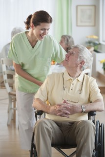 Nurse helping senior man in wheel chair.