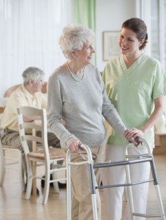 Nurse helping senior woman in walker.