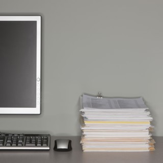 Computer and stack of paperwork.