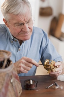 Senior man fixing fishing reel.