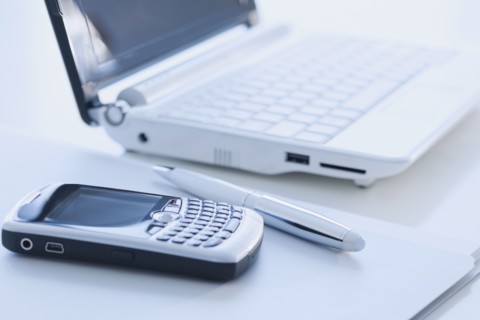 Cell phone and laptop on desk.