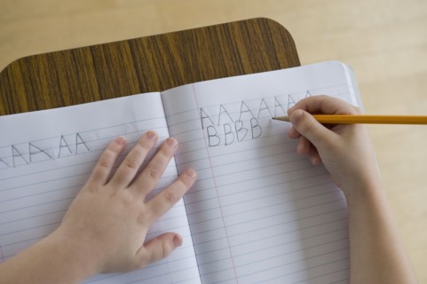 Boy writing letters in classroom.