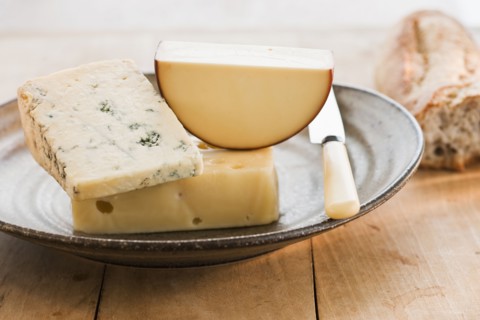 Pieces of cheese with grapes on background.
