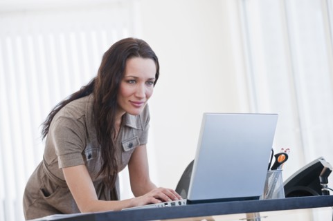 Woman using computer in office, smiling.
