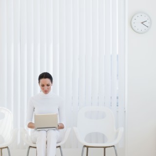 Businesswoman using laptop in waiting room.