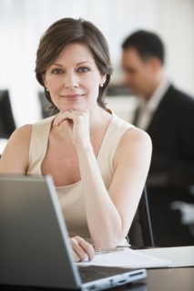 Portrait of successful mature businesswoman sitting by desk in office.