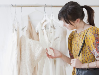 Young woman observing wedding dress in shop. Photographe : Jamie Grill