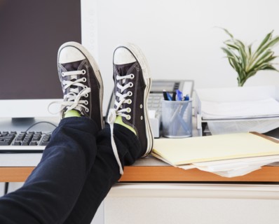 Young office worker in casual clothes relaxing in office with legs on desk. Photographe : Jamie