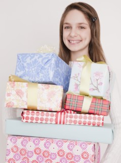 Preteen girl (10-12 years) with stack of birthday presents, smiling, portrait. Photographe : Jamie