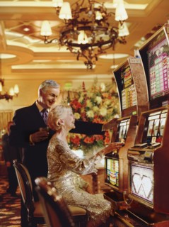 Senior couple in casino playing on slot machines, Las Vegas, Nevada, USA. Photographe : Stewart