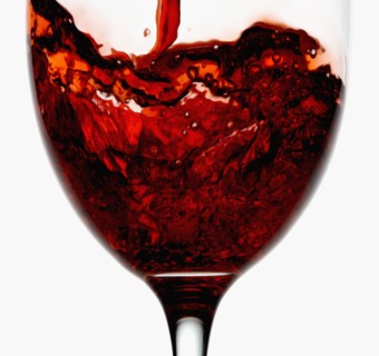 Red wine being poured into wineglass, close-up. Photographe : Joe Clark