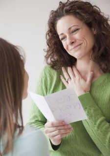 Mother receiving greeting card on mother's day from daughter (10-12 years). Photographe : Jamie