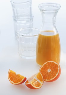 Fresh orange juice in decanter with oranges slices, studio shot.