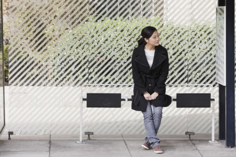 Young woman waiting at bus stop, San Francisco, California, USA. Photographe : PT Images
