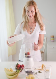 Young woman preparing fruit milkshake in liquidizer. Photographe : Jamie Grill