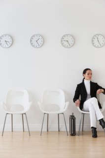 Businesswoman looking at wrist watch in waiting room.