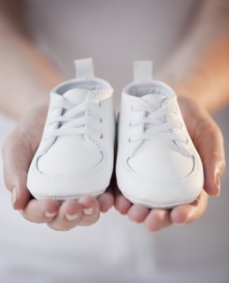 Close-up of woman holding baby shoes.