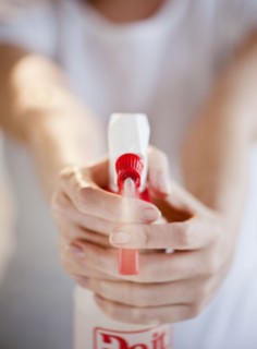 Woman holding and spraying cleaning fluid, close-up.