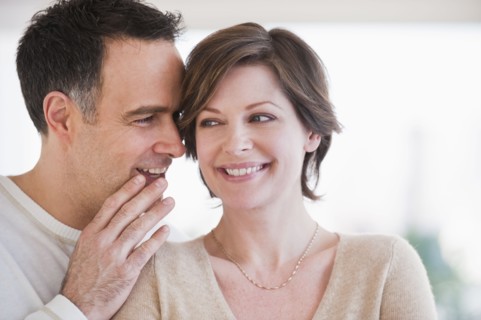 Man whispering to woman's ear.