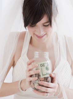 Bride holding jar of money, studio shot. Photographe : Jamie Grill
