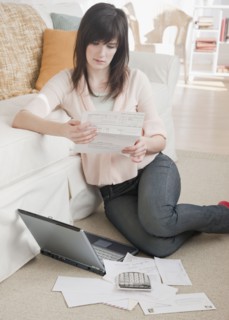 Young woman paying bills via Internet. Photographe : Jamie Grill