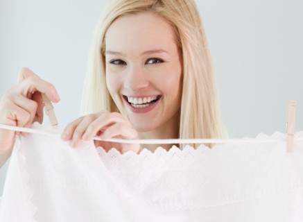 Portrait of young woman hanging laundry on washing line. Photographe : Jamie Grill