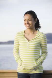 Woman standing at waterfront, smiling. Photographe : PT Images