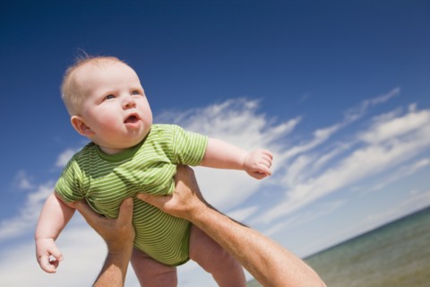 Senior man lifting baby in air, Beaver Island, Michigan, USA. Photographe : Shawn O'Connor