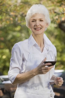 Senior woman holding glass of red wine, portrait. Photographe : mark edward atkinson