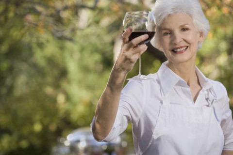 Senior woman holding glass of red wine, portrait. Photographe : mark edward atkinson