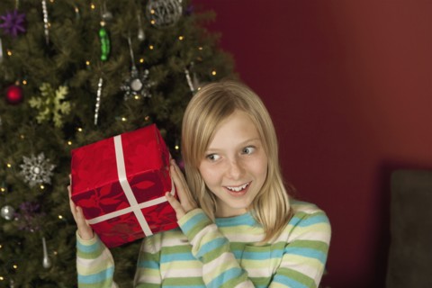 Teenage girl (10-12) shaking Christmas gift. Photographe : Sarah M. Golonka