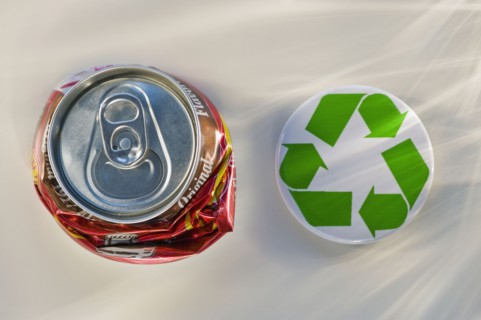 Recycling sign beside crushed can, studio shot. Photographe : Daniel Grill