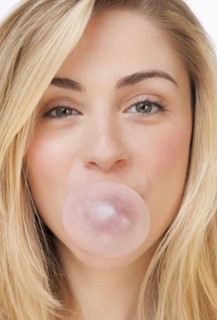 Studio portrait of young woman blowing bubble. Photographe : Daniel Grill