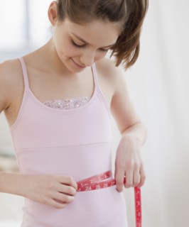Preteen girl (10-12 years) measuring waist. Photographe : Jamie Grill